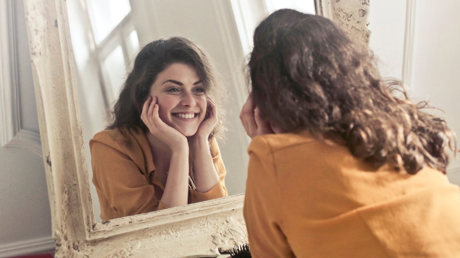 Woman looking in the mirror and smiling at herself